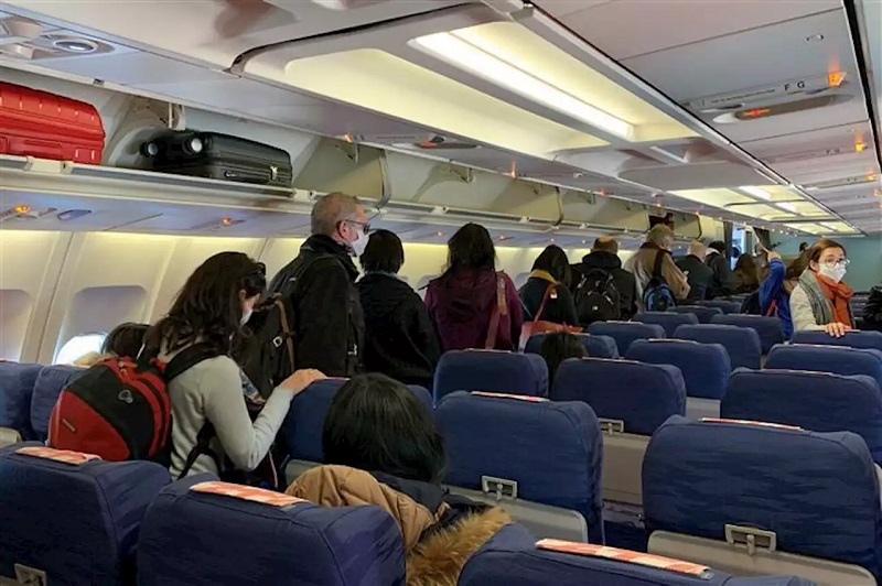 Pessoas com máscara dentro de avião